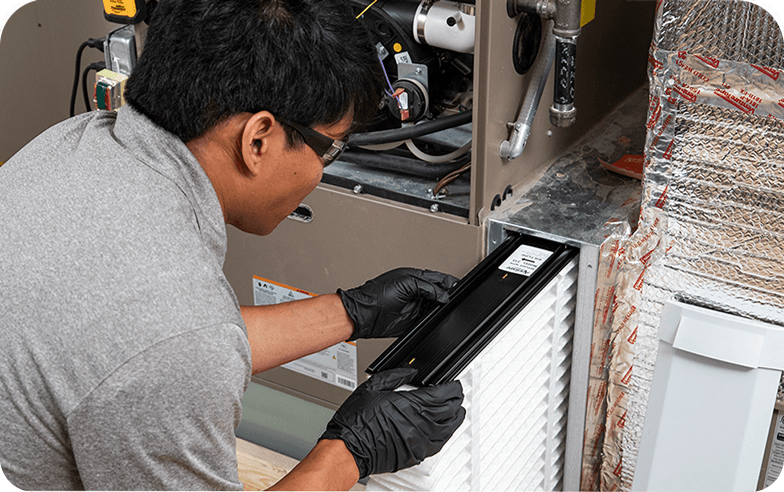 Service technician replacing an HVAC filtration system